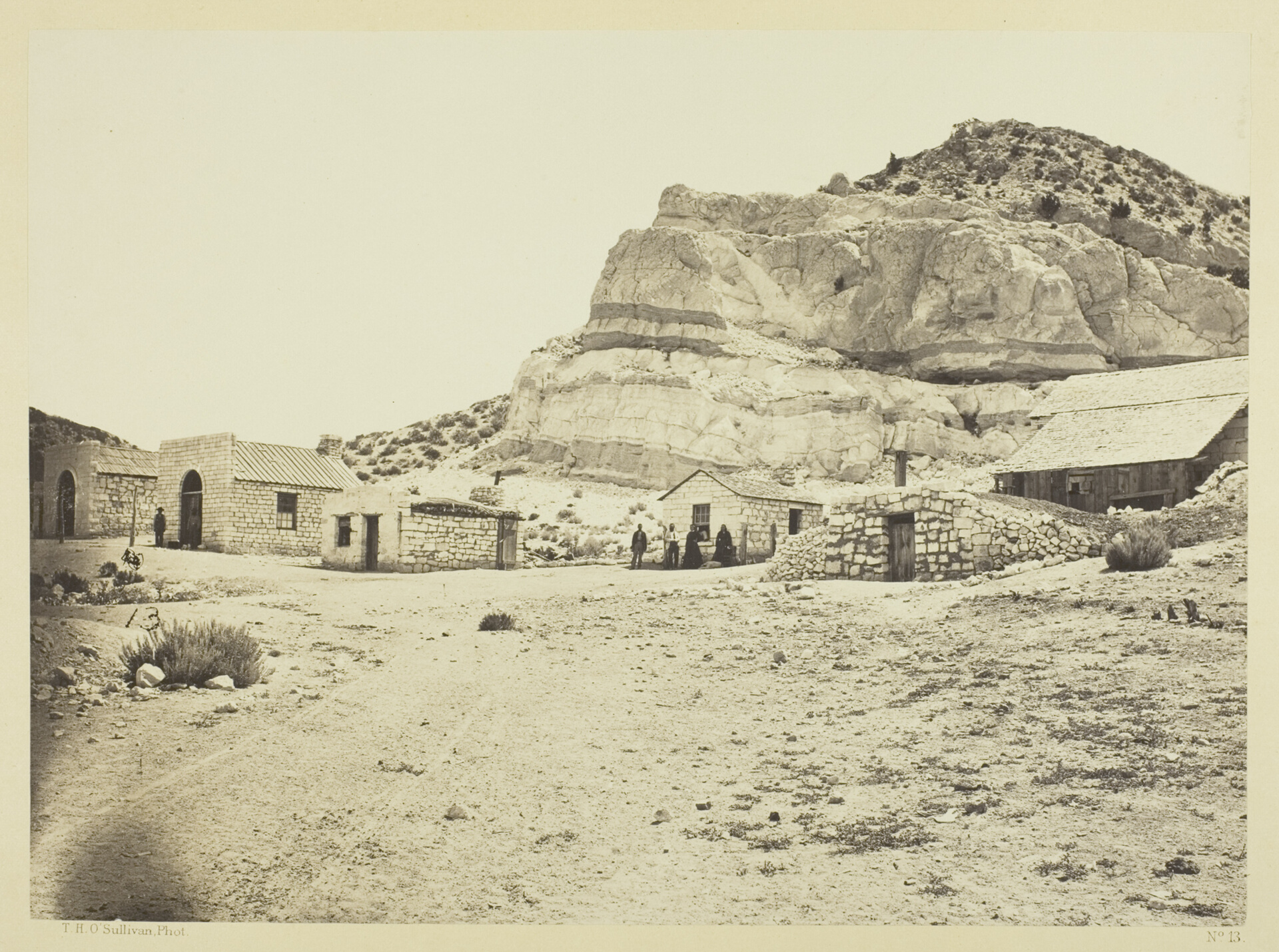 Stone buildings below layered rhyolite cliffs near Logan Springs, Nevada